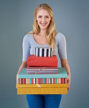 Its obvious why she gets invited to parties. Cropped studio shot of a young woman holding a stack of presents.