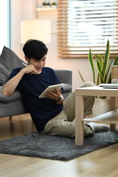 Peaceful man in casual clothes reading favorite literature in cozy living room