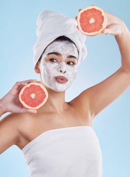 Skincare, health and face mask on a woman with a grapefruit doing an organic facial in studio. Girl with wellness, selfcare and healthy lifestyle doing a body care routine with tropical citrus fruit.