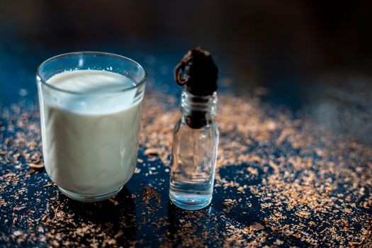 Glycerine skin cleanser on a black surface. Shot of glycerine in a glass bottle along with a glass of milk.