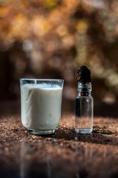 Glycerine skin cleanser on a black surface. Shot of glycerine in a glass bottle along with a glass of milk.