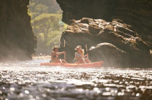 Travel, kayak and female friends on a vacation adventure while on an river or sea with a mountain view in nature. Women having fun while traveling and enjoying canoeing boat activity on holiday trip