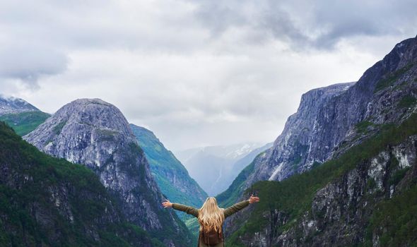 Travel adventure woman celebrates arms raised at view of majestic glacial valley on exploration discover beautiful earth
