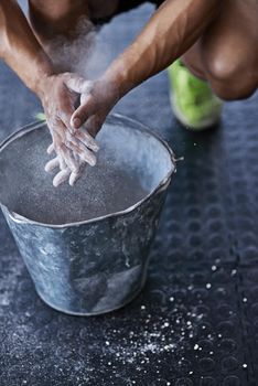 Use the chalk. a young man putting chalk powder on his hands at the gym.
