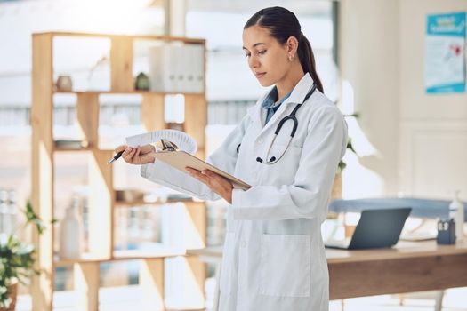 Insurance, healthcare and medicine with a doctor reading paperwork in a clipboard in her office in the hospital. Medical, review and wellness with a female professional in the health industry