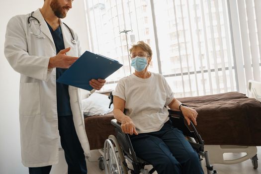 Doctor explaining to a sick patient in a wheelchair the details of treatment
