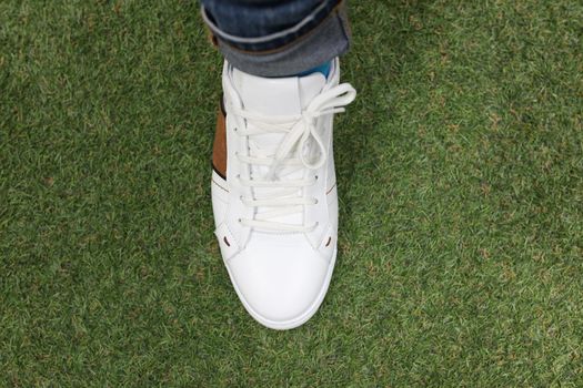 Man is wearing white sneakers on green lawn grass