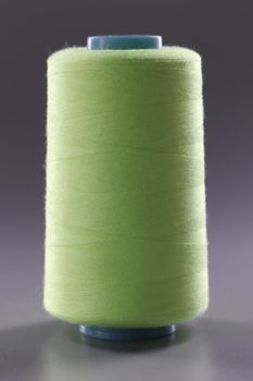 Light green spool of thread on gray background