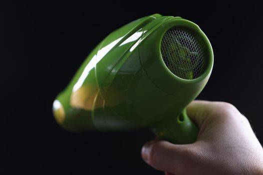 Person holds hair dryer back view and shows metal mesh covering inside of device
