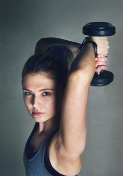 Wow means woman on weights. a young woman lifting dumbbells against a grey background.