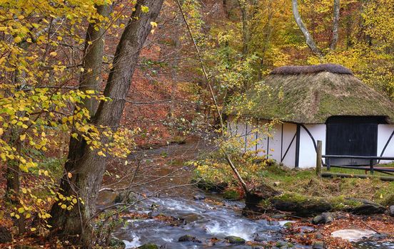 Old fishing house by the river in the forest. 250 years old public fishing house by the river in the colors of autumn.