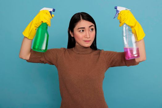 Strong serious asian housemaid raising arms from chores