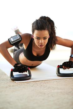 The ultimate upper body workout. a young woman exercising using push up grips.