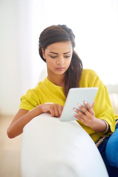 Nice and comfortable at home. a young woman using a digital tablet at home.