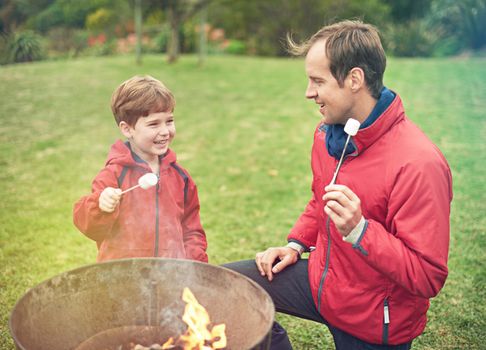 The best sweet treat ever. a father and son roasting marshmallows over a fire.