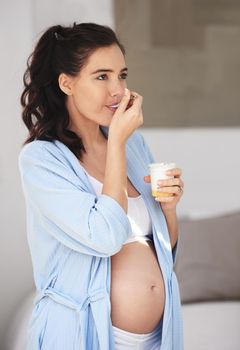 Snacking for two. a pregnant woman enjoying a snack at home.