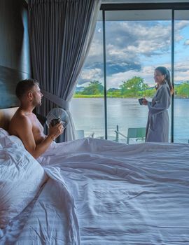 men and women in a room by the river in Thailand waking up with coffee