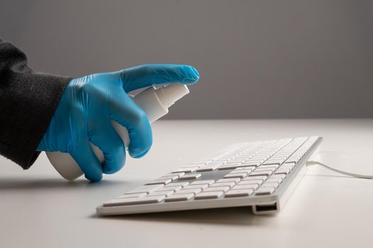 Close-up of a woman disinfects a white computer keyboard. Slow motion.