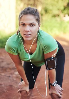 Ready to hit the trail. a young woman listening to music while out running.