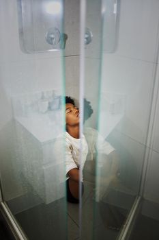 Depression, anxiety and stress girl thinking in a shower at home. Black woman suffering from mental health, anxiety and depressed after relationship, personal problem or life crisis in house bathroom