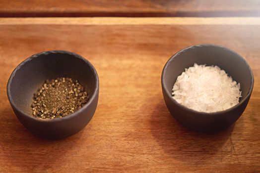 Salt and pepperits always better when were together. salt and pepper in bowls on a tabletop.