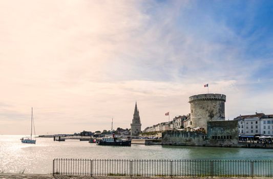 View of the entrance to the old port of the French city of La Rochelle with one of its towers at sunset.