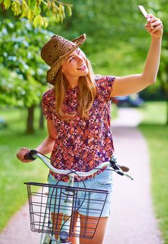 Taking a ride down memory lane. a young woman taking a selfie while out for a bike ride in the park.