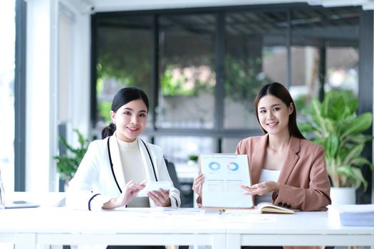 Two asian business woman work together to get the job done at the office.