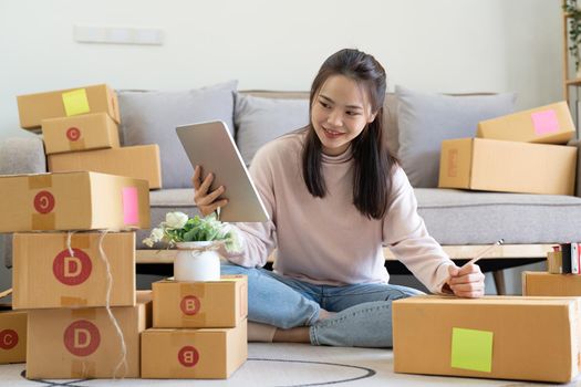 Female online store small business owner entrepreneur seller packing shipping ecommerce box checking website retail order using laptop preparing delivery parcel.