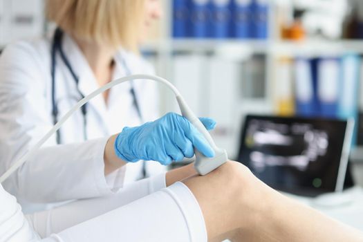 Orthopedic doctor makes ultrasound examination of patient knee in office