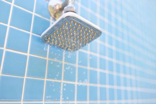 Wall-mounted outdoor shower and water drops on blue tile background