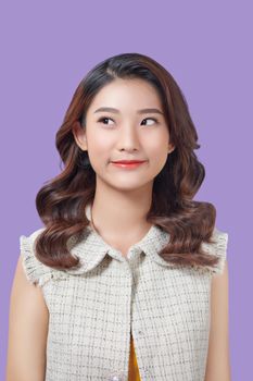 Young asian woman isolated on purple background making doubts gesture looking side