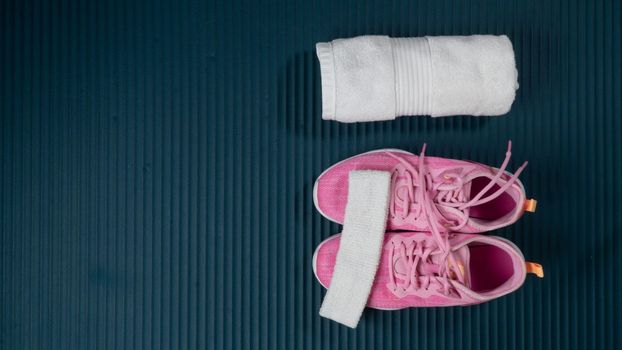 Sneakers, rolled up towel and Buff on the sports mat - space for text
