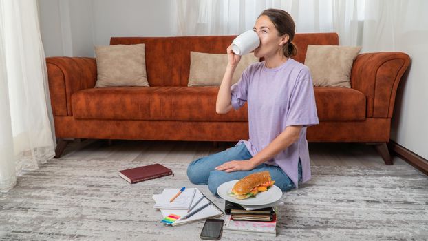 Female student drinks coffee while studying at home