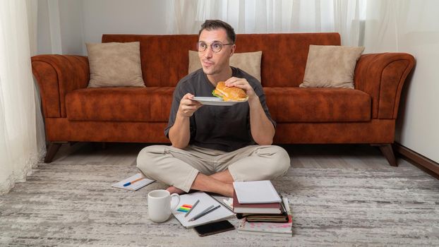 Student eats a large sandwich while studying at home