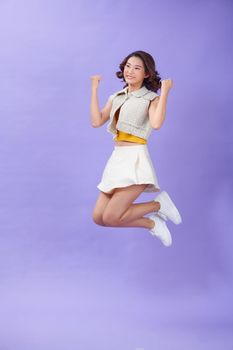 Full length photo of ecstatic girl jump win raise fists scream isolated over purple color background