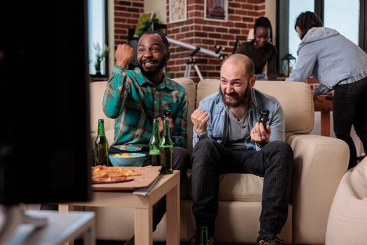 Cheerful people celebrating video games win at house gathering