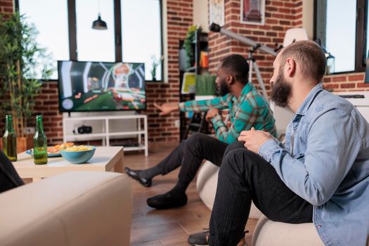 Diverse team of men using tv console to play shooter video games