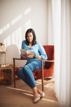 Today is technology-free. a woman sitting in her living room reading a book.