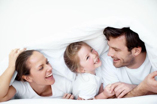 I love playing with my mom and dad. A young girl playing with her mother and father under bedsheets.