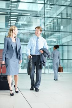 Heading out to a corporate conference. Smiling mature businesspeople arriving at an airport with their suitcases - Business Travel.