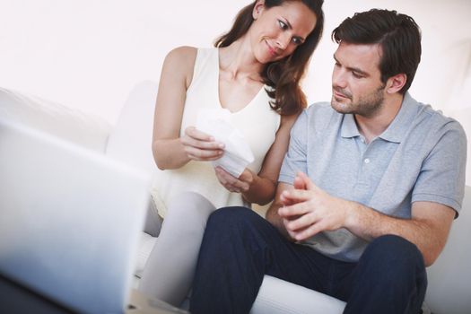 Hes proud of his wifes budgeting skills. A married couple inspecting bills as they do their home finances.