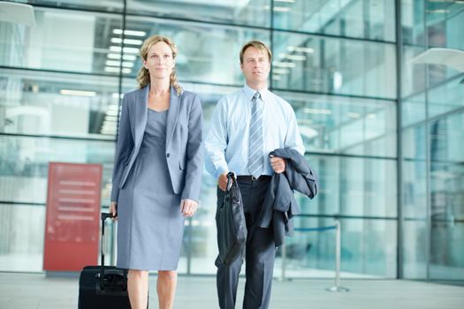 Heading to an important conference. Determined mature businesspeople arriving at an airport with their suitcases - Business Travel.