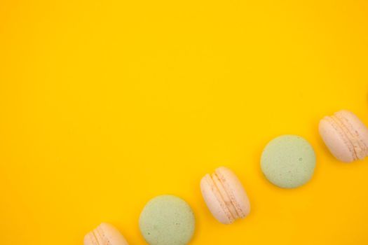 Row of colorful french macarons over yellow background