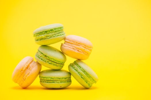 Delicate sweet french macaroons over yellow background