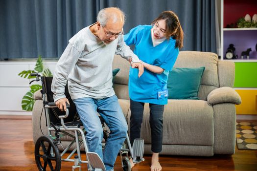 Doctor support old man to getting up to exercise, help handicapped elderly stand up