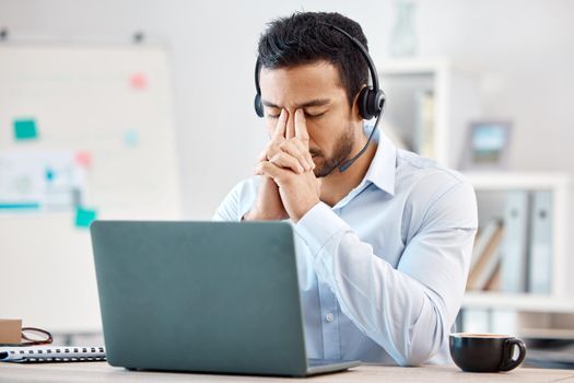 Stress, headache and depression of call center agent feeling overwhelmed, upset and frustrated while wearing headset and using laptop at desk. Male crm, telemarketing and customer support operator