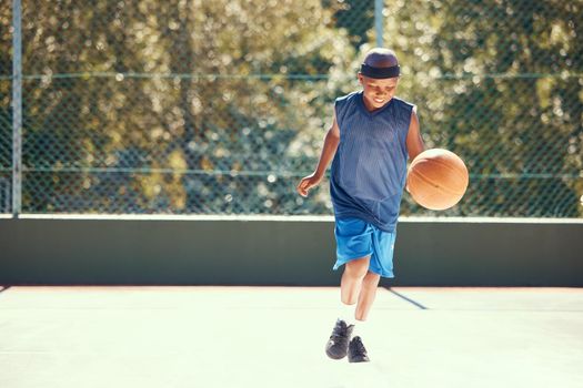 Sports, athlete and child basketball player training for a match on an outdoor court in nature. Exercise, workout and healthy boy practicing his skill for a game on a professional field.