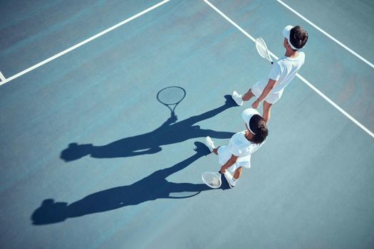 Sport, fitness and tennis player team discussion of game strategy while walking together on a tennis court from above. Professional, athletic and competitive man and woman planning and training