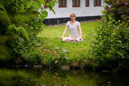 At one with nature. a woman sitting in the lotus position in her backyard.